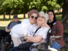 Pflegekraft und Seniorin lächeln gemeinsam im Park