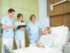 Pflegefachkräfte am Bett mit Patientin mit WSSRK Tasse